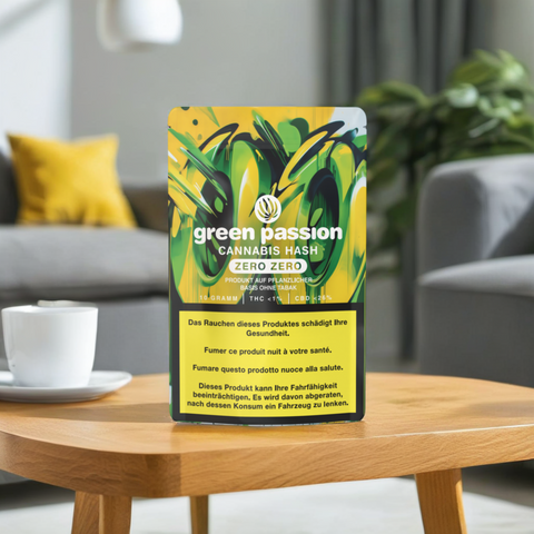 Edle Verpackung des CBD Hash Zero Zero von Green Passion auf Holztisch, stilvolle Wohnzimmer-Szene mit Couch im Hintergrund.